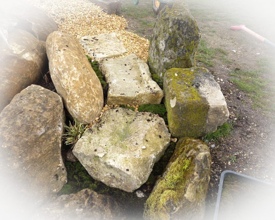 Moss-covered stones arranged as part of a soft landscaping project, creating a natural garden feature